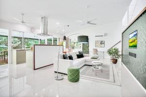a white living room with a couch and a table at Villa Vihara Rainforest Penthouse in Innisfail