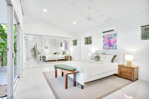 a white bedroom with a bed and a table at Villa Vihara Rainforest Penthouse in Innisfail