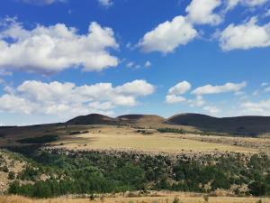 una vista su un campo e sulle colline sotto un cielo nuvoloso di Crystal Springs Mountain Lodge a Pilgrim's Rest