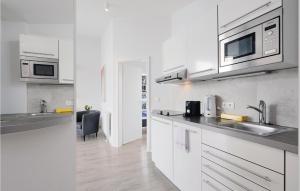 Una cocina blanca con fregadero y microondas. en Dünenvilla 21, Whg 10, en Travemünde
