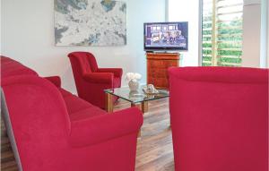 a living room with two red chairs and a tv at Cozy Home In Kuhlen Wendorf With Wifi in Wendorf