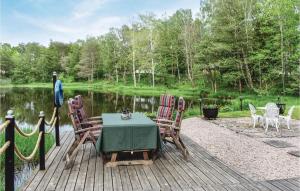 a table and chairs on a wooden deck next to a lake at Lovely Home In Klippan With Sauna in Klippan