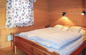 a large white bed in a wooden room with a window at Nice Home In Lavik With 3 Bedrooms And Wifi in Lavik
