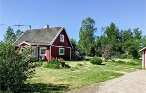 een rood huis in een tuin met een oprit bij Cozy Home In Holmsj With Kitchen in Holmsjö