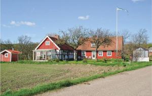 ein rotes Haus auf einem Feld neben einer Straße in der Unterkunft Pet Friendly Home In Hjrnarp With Wifi in Hjärnarp