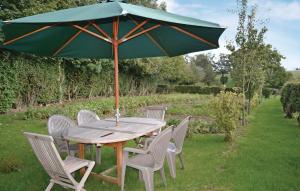 a wooden table with chairs and a green umbrella at Nice Home In Senlecques With Kitchen in Senlecques
