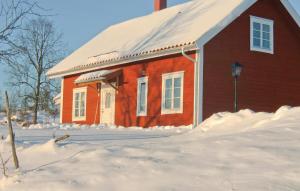 uma casa vermelha com neve em frente em Nice Home In Vetlanda With Wifi em Skirö