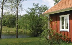 LångarydにあるTwo-Bedroom Holiday Home In Langarydの川辺の窓付き赤い家