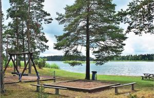 a picnic table and a swing set next to a lake at Okn in Mönsterås