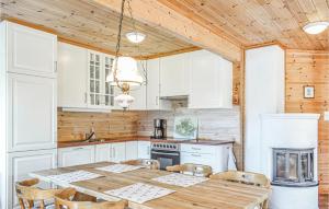 uma cozinha com armários brancos e uma mesa e cadeiras de madeira em Nice Home In Vaksdal With House A Mountain View em Stavenesli
