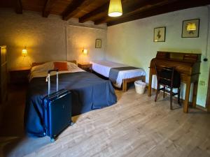 a bedroom with two beds and a piano and a suitcase at El Buxaus de la Muntanya in Arbúcies