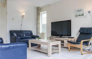 ein Wohnzimmer mit einem TV, 2 Stühlen und einem Tisch in der Unterkunft Pet Friendly Home In Vlagtwedde With Indoor Swimming Pool in Vlagtwedde