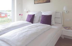 ein weißes Bett mit weißer Bettwäsche und lila Kissen in der Unterkunft Ferienhaus Dageb�ll K�stenweg VI in Dagebüll