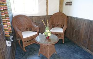 two wicker chairs and a table with a vase of flowers at Cozy Apartment In Sandnes With Kitchen in Bråstein