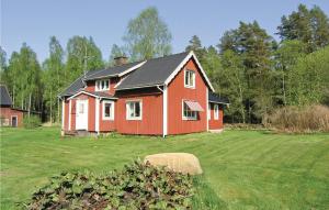una casa rossa con un tetto nero in un cortile di Gorgeous Home In Lngaryd With Kitchen a Långaryd