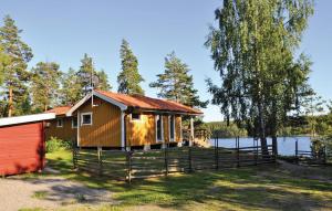 a house with a fence in front of a lake at Amazing Home In Frseke With House Sea View in Fröseke