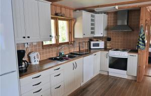 a kitchen with white cabinets and white appliances at Amazing Home In Frseke With House Sea View in Fröseke