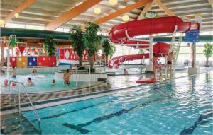 een zwembad met een glijbaan en mensen in het water bij Awesome Home In Vlagtwedde With 3 Bedrooms, Wifi And Indoor Swimming Pool in Vlagtwedde