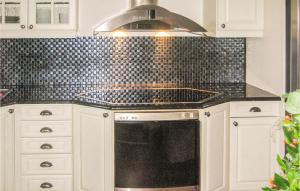 a kitchen with a stove and a black tile wall at 4 Bedroom Stunning Home In Rong in Rong