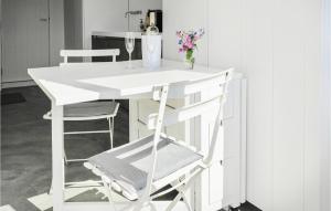 ein weißer Schreibtisch mit einem Stuhl und einer Vase mit Blumen in der Unterkunft Windwijser in Bergen aan Zee