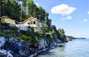 a house on a cliff next to the water at Beautiful Home In Nordre Frogn With 3 Bedrooms in Brevik