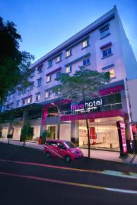 een roze auto geparkeerd voor een gebouw bij favehotel Melawai in Jakarta
