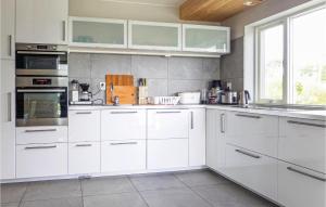 uma cozinha branca com armários brancos e uma janela em Lovely Apartment In Bokn With House Sea View em Kro
