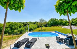 a swimming pool with a group of chairs and trees at Cozy Home In Dragoslavec With Kitchen in Praporčan