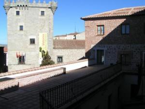 a building with a balcony next to a castle at Palacio Duque de Tamames - HOTEL EL RASTRO in Ávila