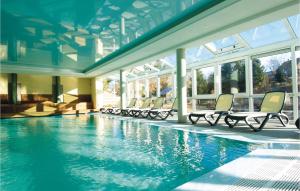 a swimming pool with chairs in a building at Hotel Drosson in Wirtzfeld