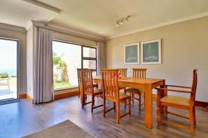 a dining room with a wooden table and chairs at Sea Cliff Condo in Knysna