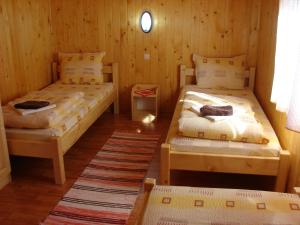 twee bedden in een kamer met houten wanden bij Korondi Kulcsosházak in Corund