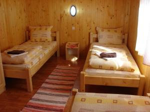two beds in a room with wooden walls at Korondi Kulcsosházak in Corund