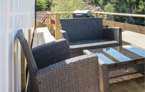 two wicker chairs and a glass table on a patio at Nice Home In Staubø With House Sea View in Staubø
