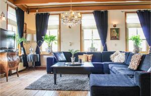 Cozy Home In Visvliet With Kitchen في Visvliet: غرفة معيشة بها أريكة زرقاء وثريا