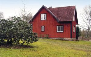 a red barn with a black roof on a green field at Cozy Home In Lngaryd With Kitchen in Långaryd