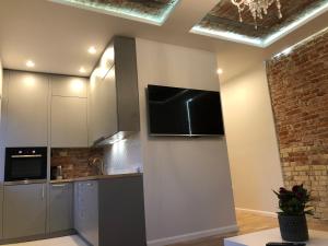 a kitchen with white cabinets and a flat screen tv at Old Town Deluxe Apartment in Klaipėda