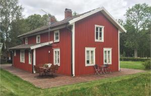 a red house with a deck and a table at 2 Bedroom Amazing Home In Unnaryd in Unnaryd