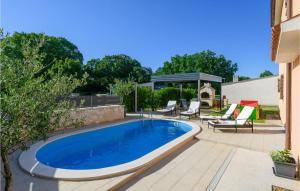 einen Pool in einem Garten mit Stühlen und einer Terrasse in der Unterkunft Stunning Home In Dobrani With Wifi in Rebići