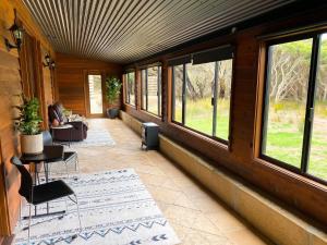 a screened in porch with windows and a person sitting on a couch at Peacehaven Chalet on the Irwin Inlet in Bow Bridge