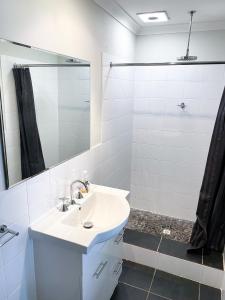 a white bathroom with a sink and a shower at Peacehaven Chalet on the Irwin Inlet in Bow Bridge