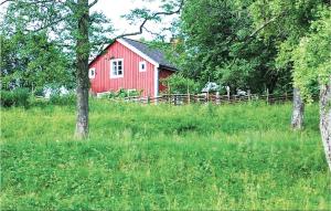 a red barn in the middle of a field with trees at Gorgeous Home In Sävsjö With Wifi in Bodafors