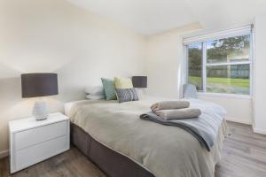 1 dormitorio con 1 cama con mesita de noche y ventana en Point Grey Apartment 13, en Lorne