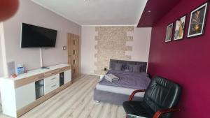 - une chambre avec un mur violet, un lit et une chaise dans l'établissement Apartament Centrum Arma Plac Rodła, à Szczecin