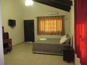 a bedroom with a bed and a television and a window at Moony’s Chalets & Camping in Catembe