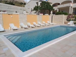 - une piscine avec chaises longues et une maison dans l'établissement Apartment Ante K A1, à Metajna