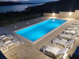 a swimming pool with chairs and a swimming pool at Apartment Ante K A1 in Metajna