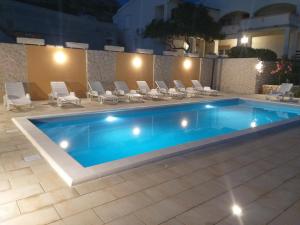 a swimming pool with a bunch of chairs around it at Apartment Ante K A1 in Metajna