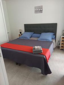 a bed with blue and red sheets and blue pillows at hébergement figari in Figari
