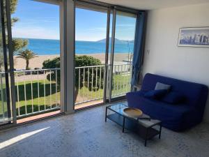 a living room with a blue couch and a view of the ocean at Appartement vue sur mer in Argelès-sur-Mer